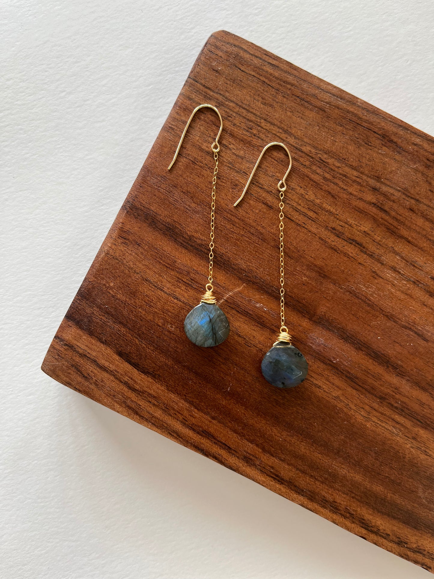 14k gold filledLabradorite dangle earrings laying against a piece of wood.